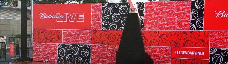Large Budweiser Live event banner with red and black design at a festival.