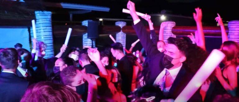 Students dancing at prom with glow sticks and vibrant lighting.