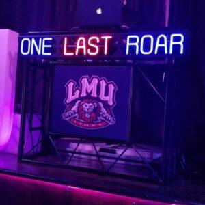 Neon DJ booth featuring "One Last Roar" sign and LMU logo, perfect for corporate and private events.